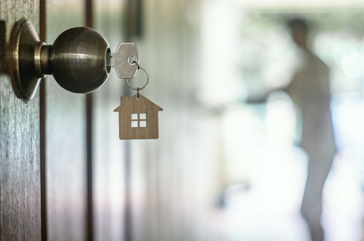 house key with home keyring in keyhole on wood door copy space picture id1140575447
