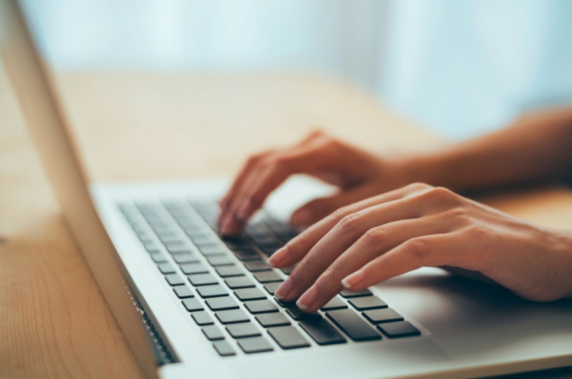 Woman hands typing on laptop keyboard at the office
