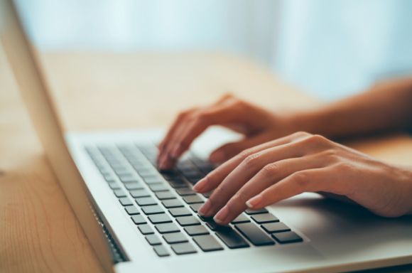 Woman hands typing on laptop keyboard at the office