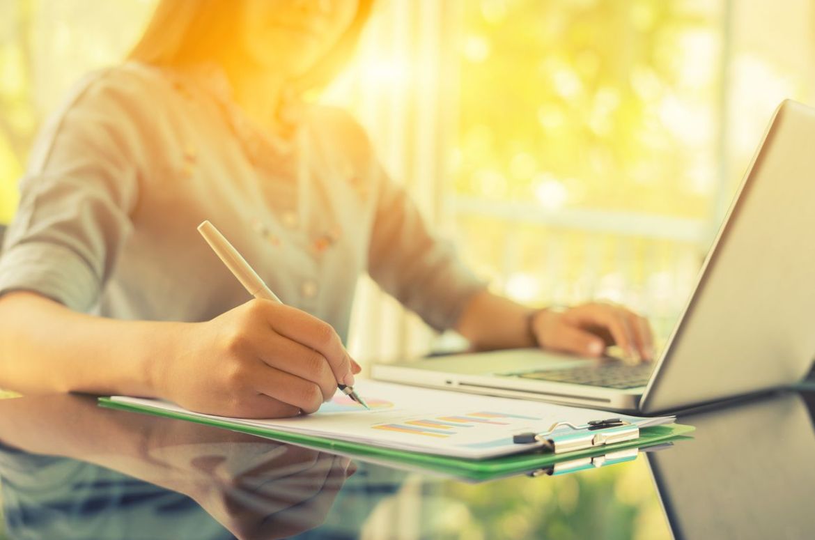 Woman with laptop writing notes