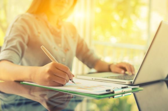 Woman with laptop writing notes