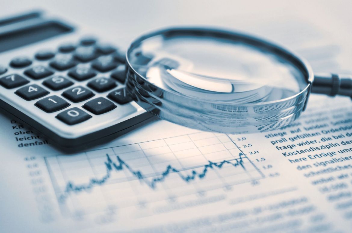 Magnifying glass and calculator on financial papers