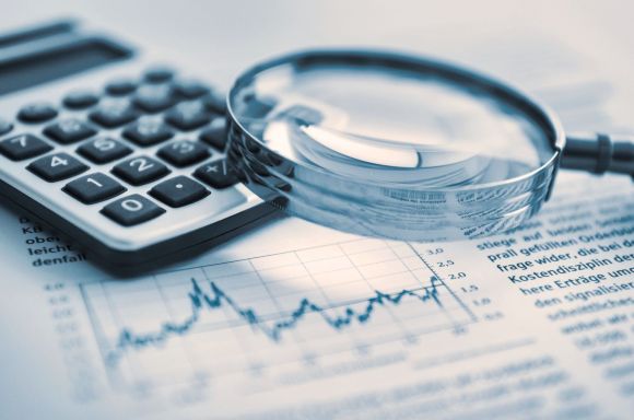 Magnifying glass and calculator on financial papers