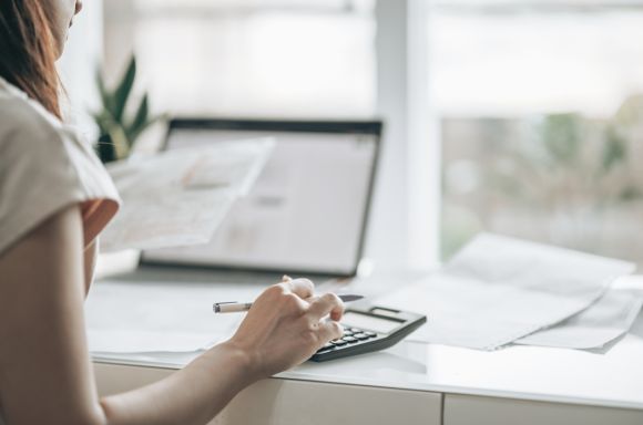 Woman using calculator doing taxes in home office