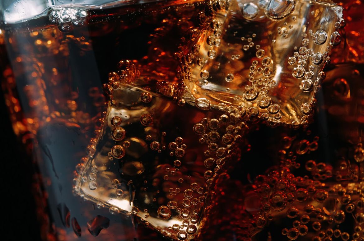 Close-up of a glass of cola with ice cubes and bubbles