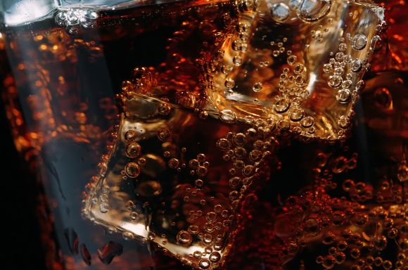 Close-up of a glass of cola with ice cubes and bubbles