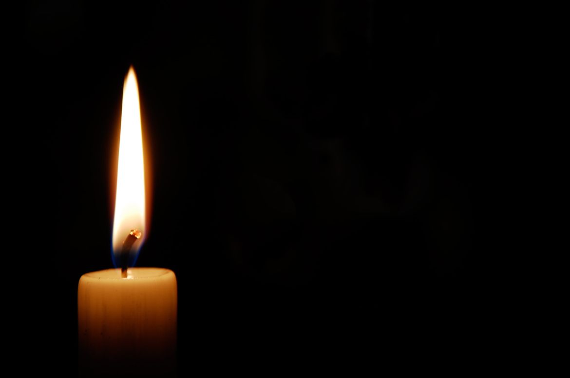 White candle burning in the dark