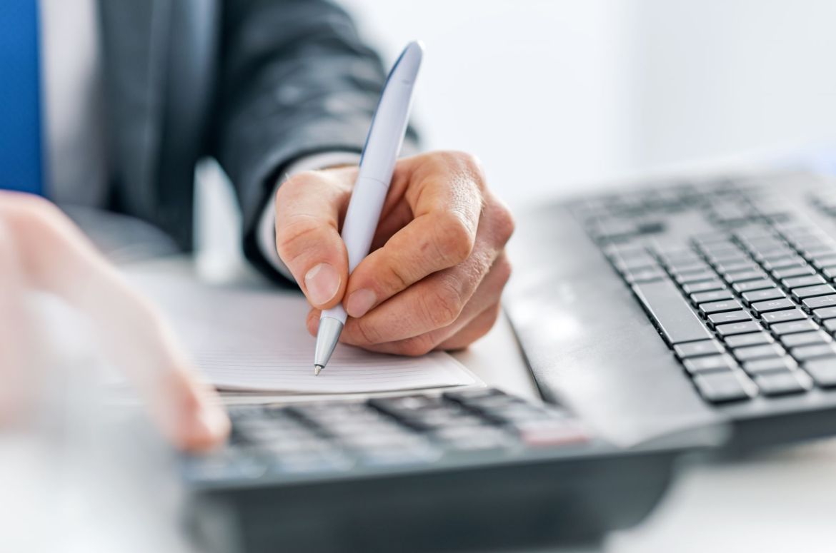 man writing with calculator