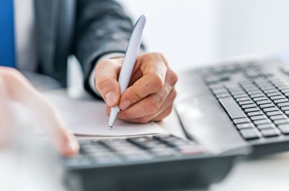 man writing with calculator