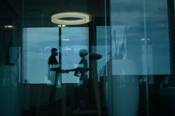 Silhouetted shot of two businesspeople shaking hands in an office