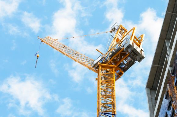 Close up construction crane next to bulding blue sky v2