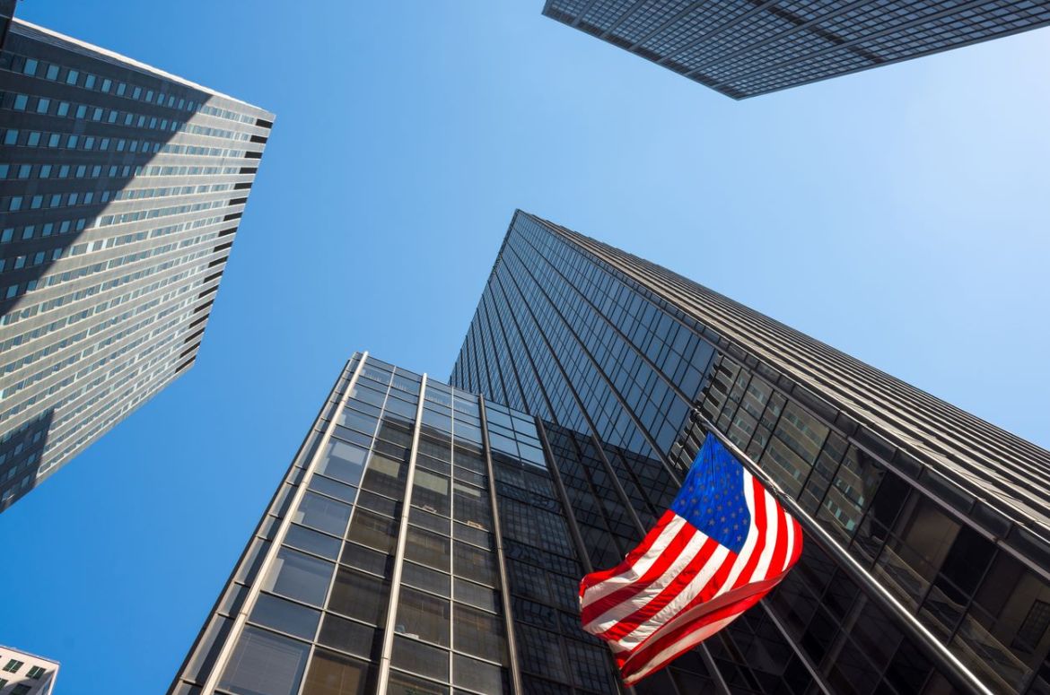 Skyscrapers and an American flag waving in mid town Manhattan