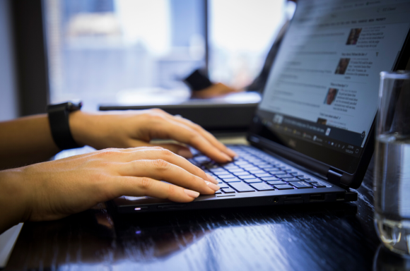 Woman using laptop to browse newspaper